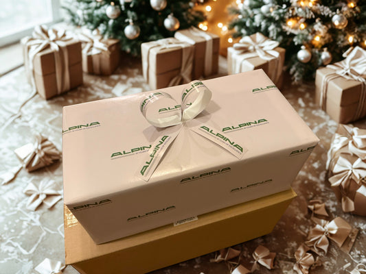 Gift box with 'Alpina' branding on a festive background with Christmas trees and presents.